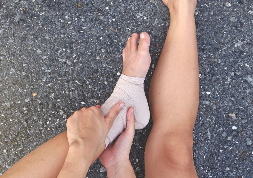 injured runner sitting on the floor with a bandaged ankle